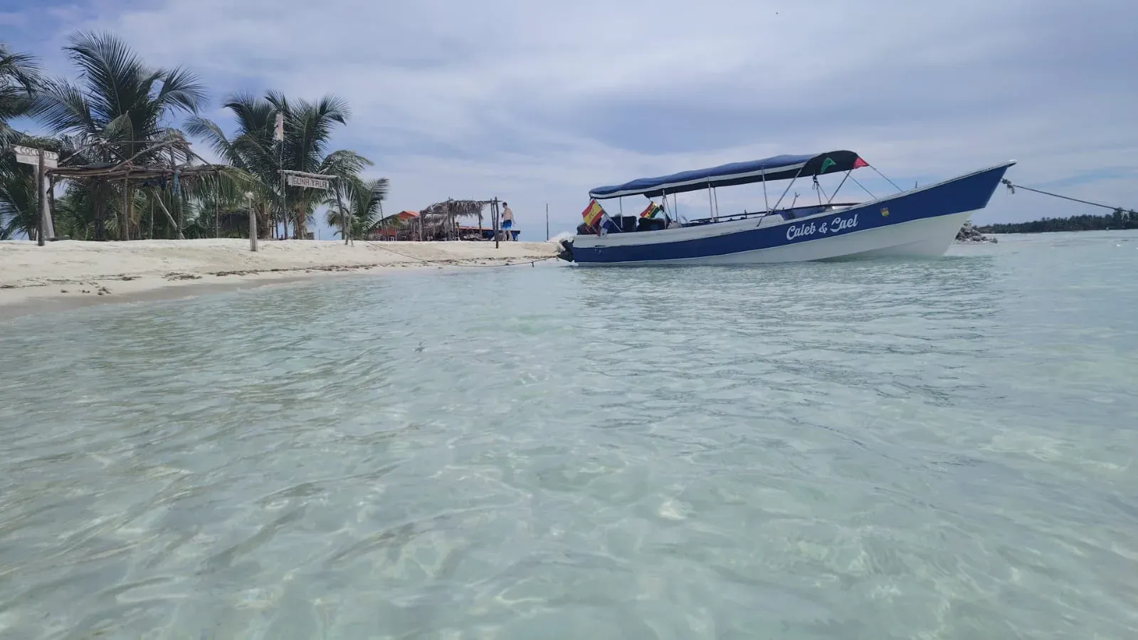 Lancha Caleb y Cael anclada frente a una playa con palmeras