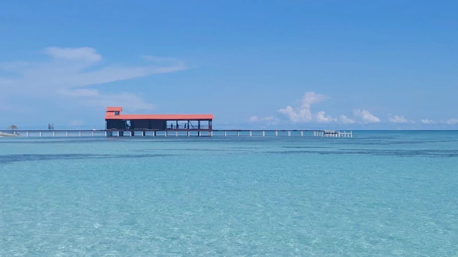 Muelle con techo naranja sobre agua turquesa cristalina